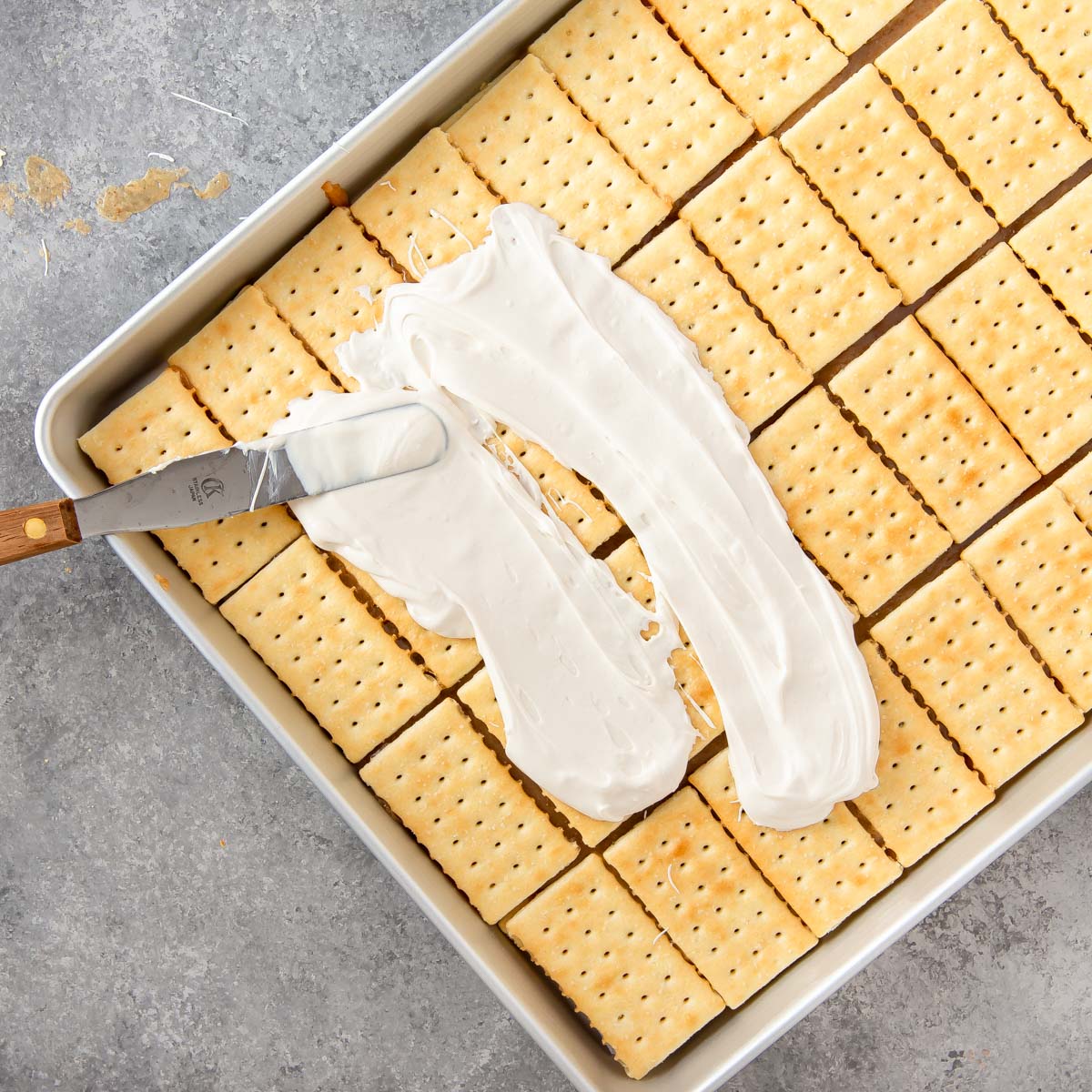 spreading melted white chocolate on toffee bars